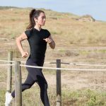 Woman jogging on a sunny day on a wooden path in Portugal, embracing a healthy lifestyle.